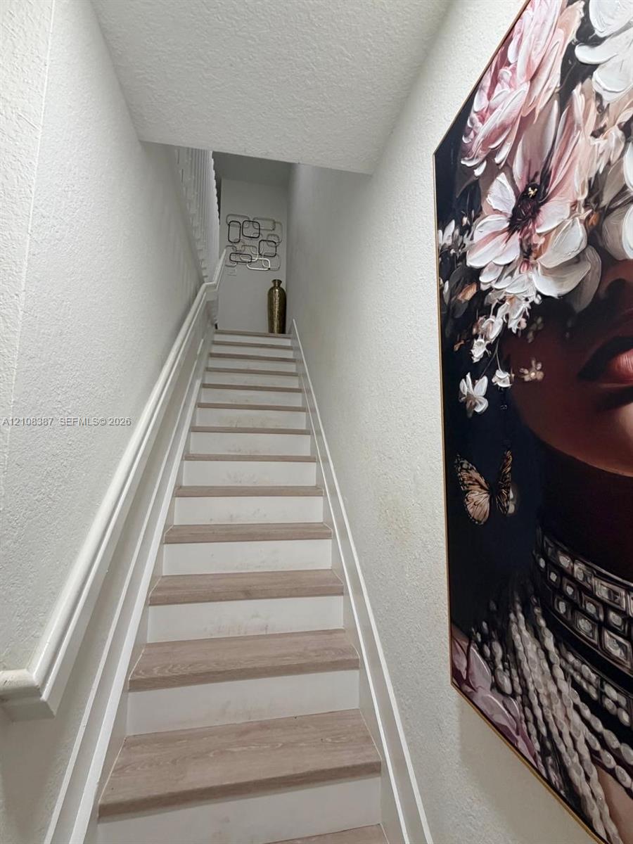 Staircase featuring wood-finish treads, white risers, and a continuous white-painted handrail