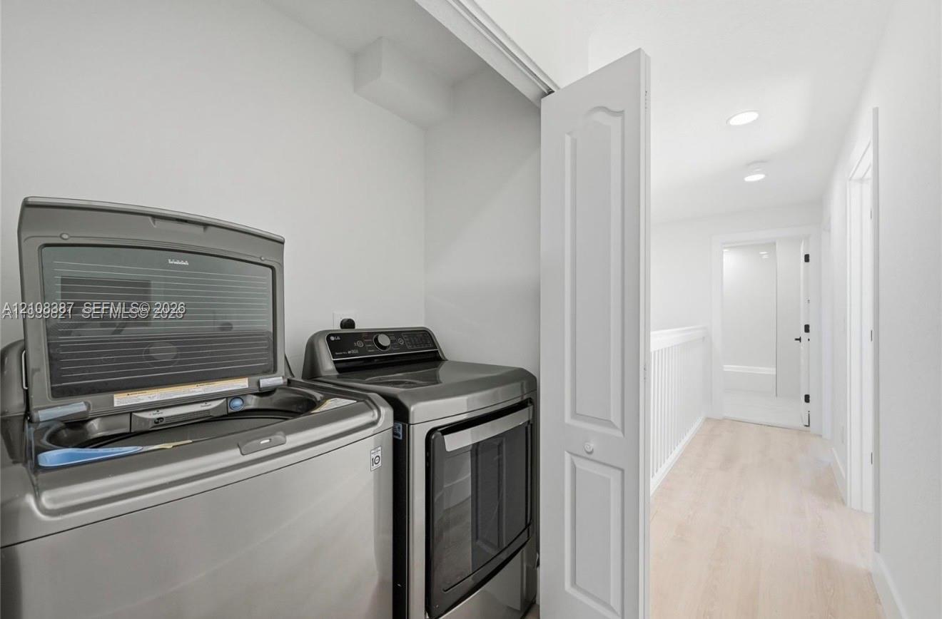Laundry area featuring recessed ceiling lighting, bifold closet door, and wood-finish flooring