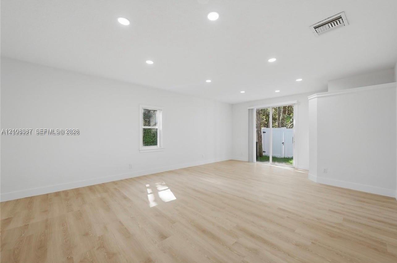Open-concept space featuring wood-finish flooring, recessed lighting, and a glass sliding door