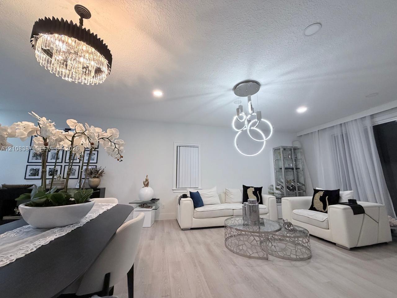 Open concept room featuring recessed lighting, modern geometric ring chandelier, contemporary tiered drum pendant light, and light-tone wood-finish flooring