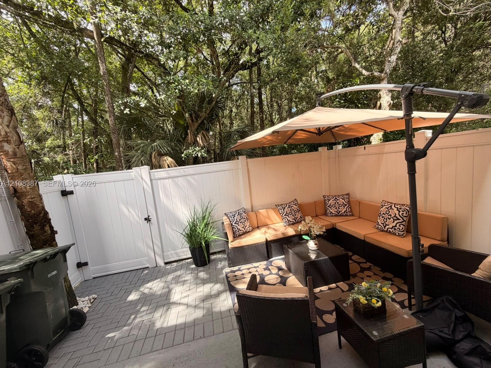 Private patio featuring gray herringbone pavers and a solid white vinyl privacy fence