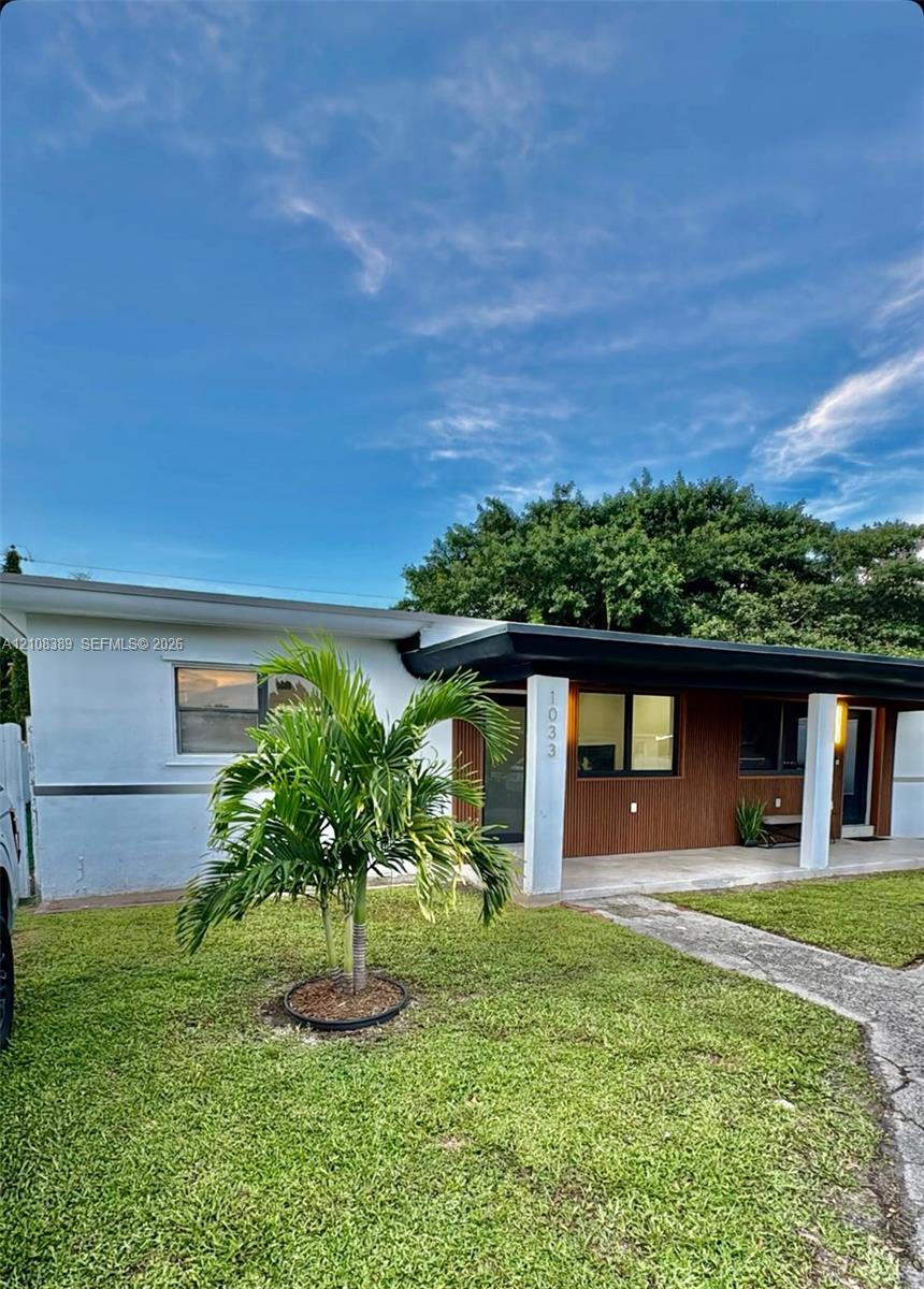 Exterior featuring a combination of white stucco and wood-finish siding, a covered entryway with square support columns, and a concrete walkway