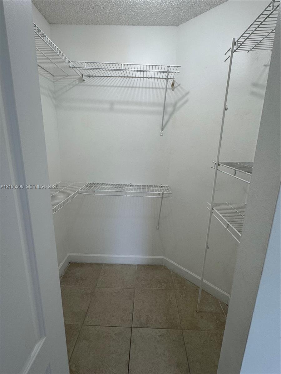 Walk-in storage space featuring ceramic tile flooring and multi-level wire shelving Walk-in storage space featuring ceramic tile flooring and multi-level wire shelving