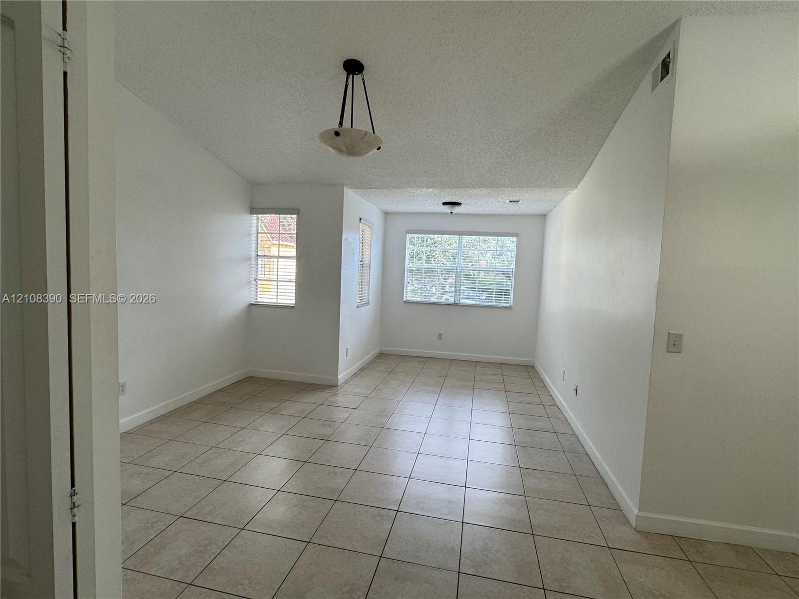 Vaulted ceilings featuring pendant lighting, ceramic tile flooring, and multiple windows with integrated blinds Vaulted ceilings featuring pendant lighting, ceramic tile flooring, and multiple windows with integrated blinds