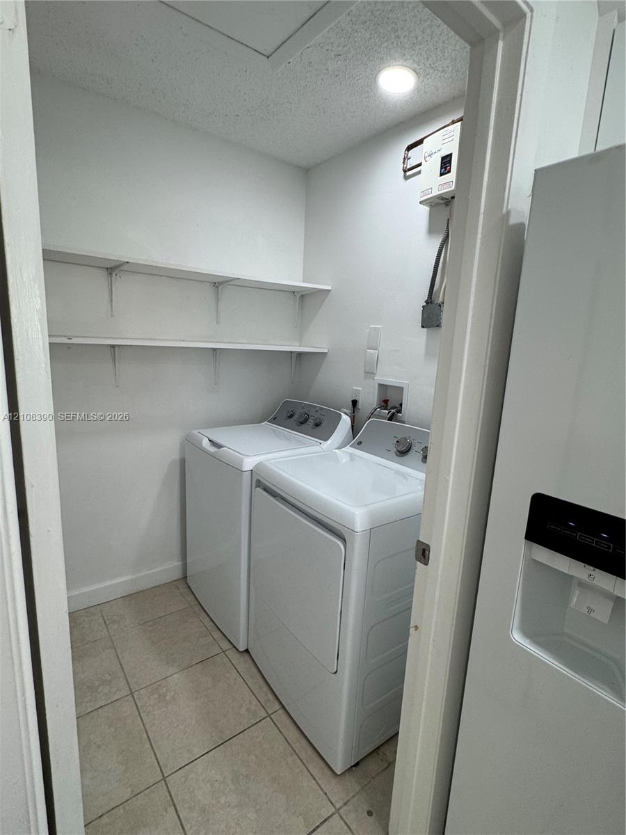 Laundry closet featuring tile flooring, built-in shelving, and dedicated hookups for a washer and dryer Laundry closet featuring tile flooring, built-in shelving, and dedicated hookups for a washer and dryer