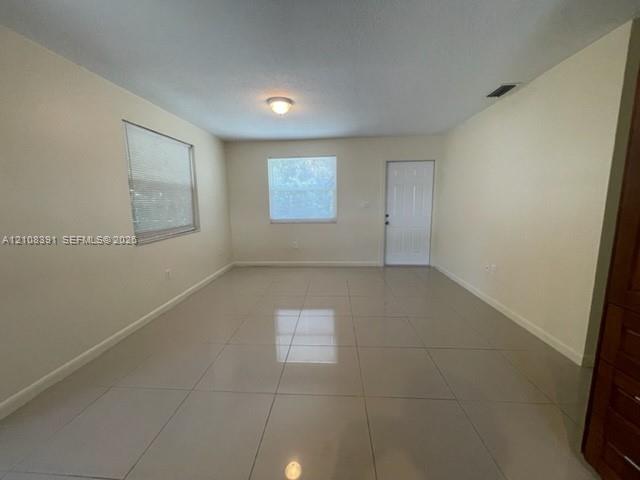 Neutral-toned tile flooring, recessed ceiling lighting, and multiple windows providing natural light