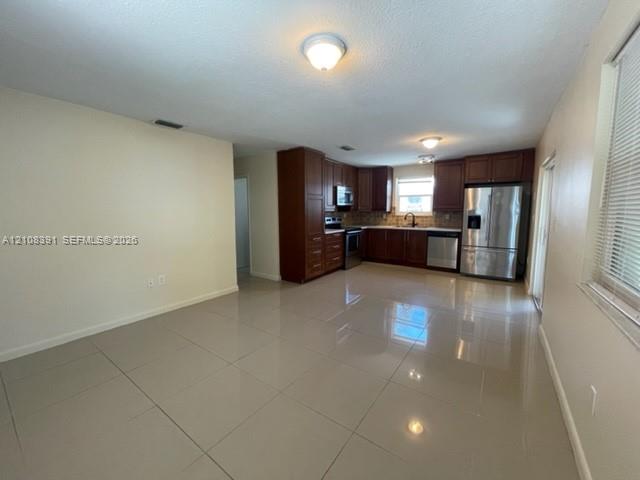 Kitchen featuring dark wood cabinetry, stainless steel appliances, and large-format tile flooring