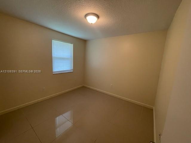 Interior room featuring large-format tile flooring, neutral wall paint, and a single-window configuration with integrated blinds