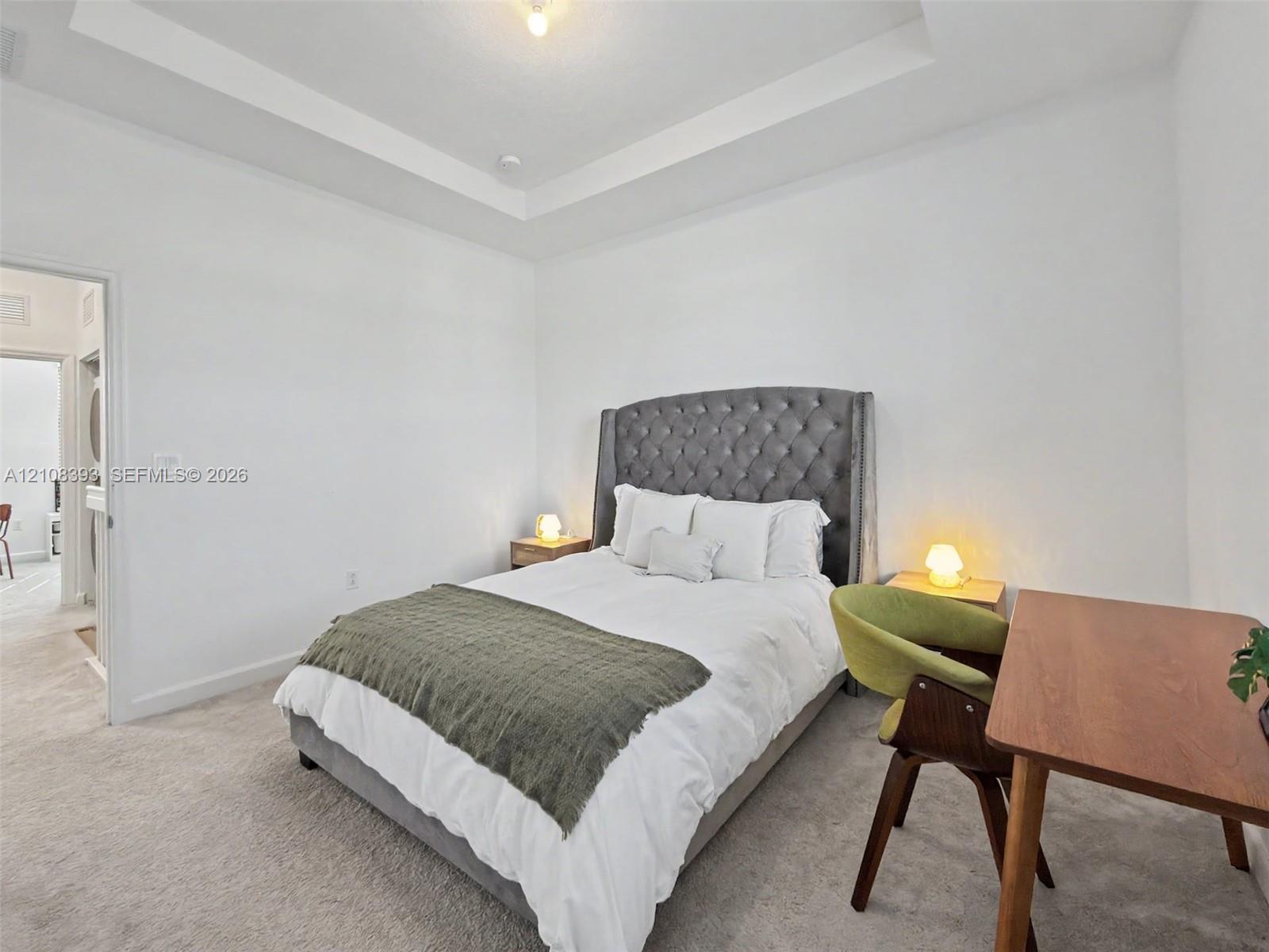 Room featuring a tray ceiling and neutral-toned wall-to-wall carpeting