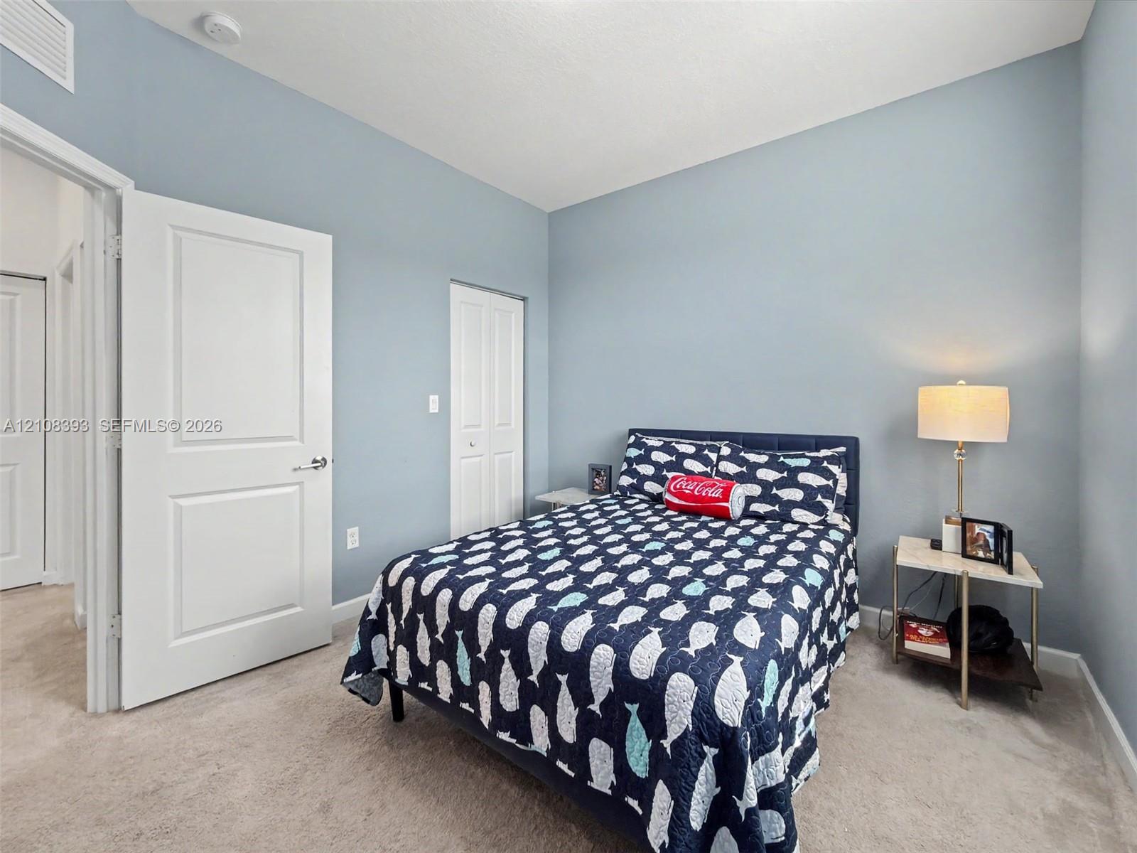 Neutral-toned interior space featuring wall-to-wall carpeting, light blue painted walls, and white multi-panel interior doors