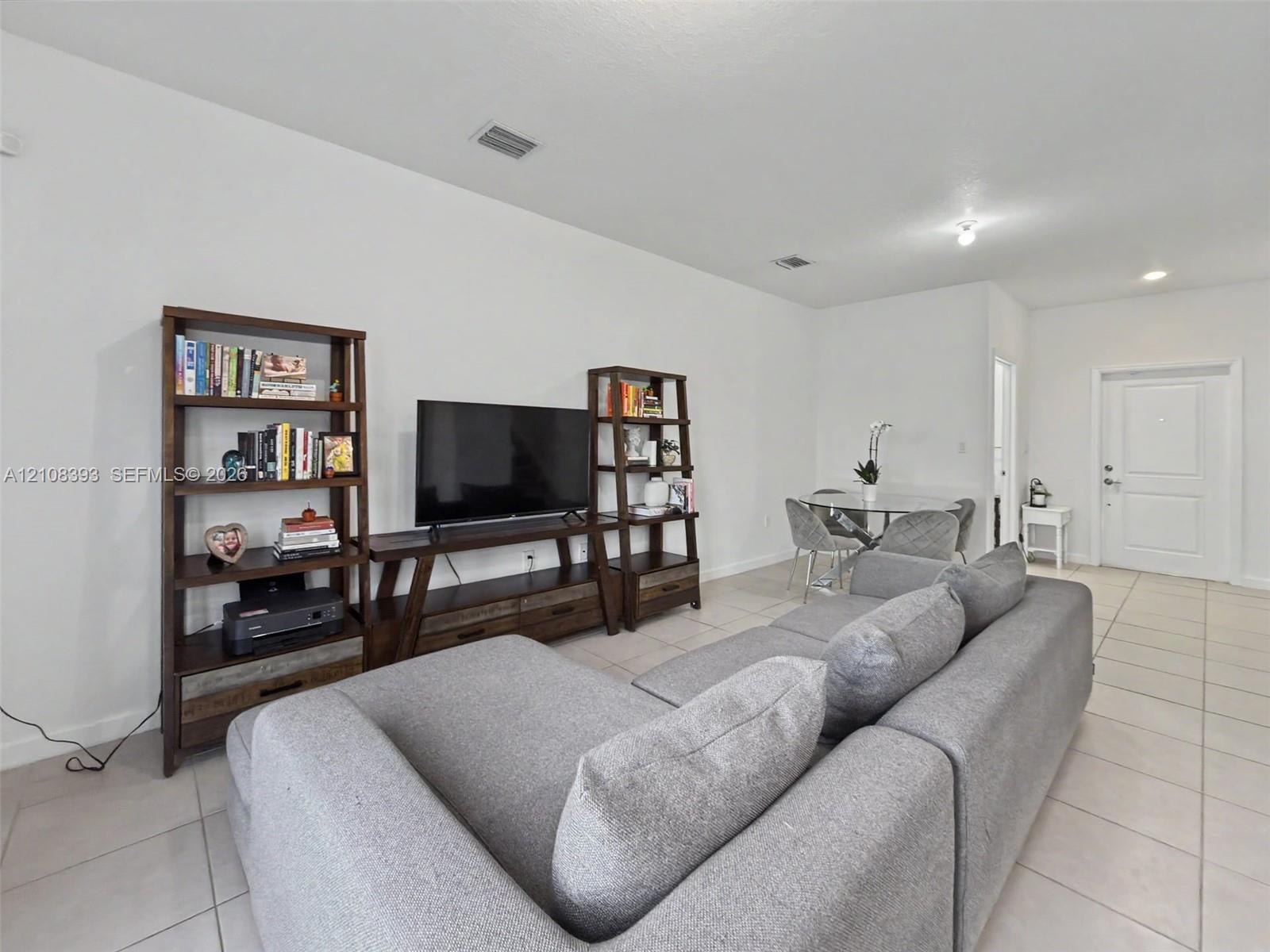 Neutral ceramic tile flooring, high ceilings, recessed lighting, and a paneled entry door