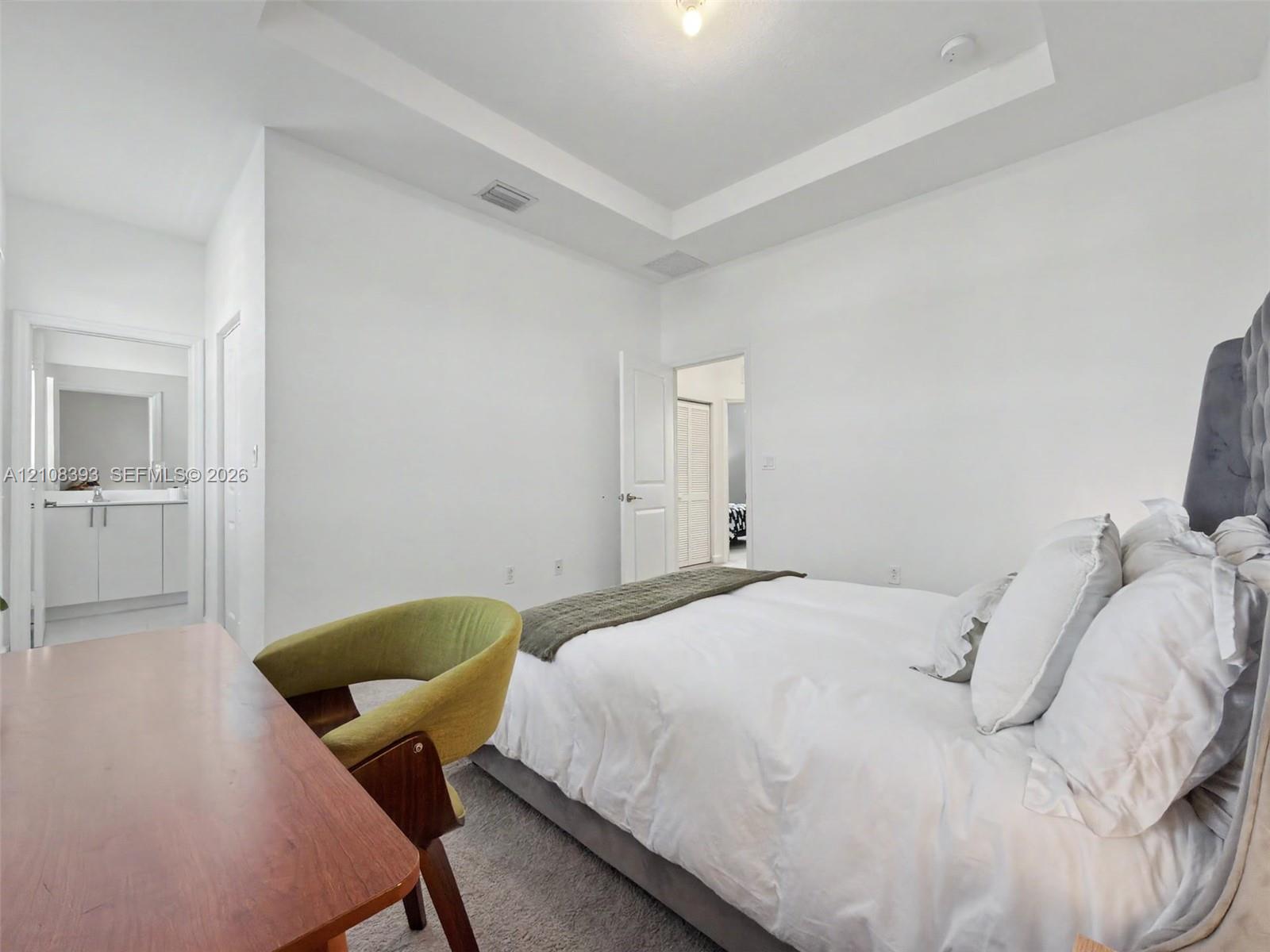 Bedroom featuring a tray ceiling, neutral carpet flooring, and paneled interior doors
