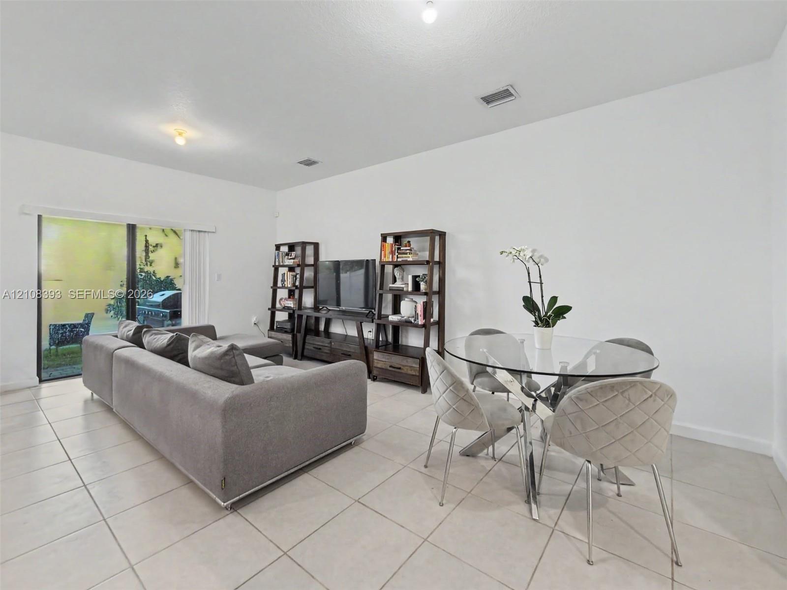 Neutral tile flooring, expansive sliding glass door, and recessed lighting