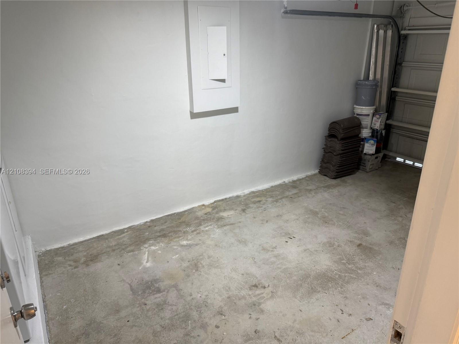 Enclosed storage area featuring concrete flooring, smooth wall finish, and an integrated electrical panel