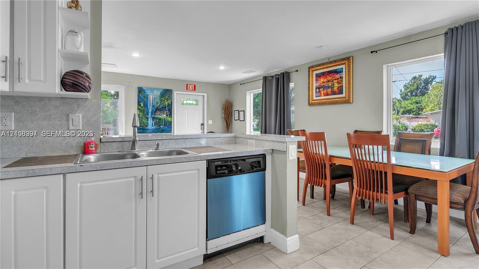 Kitchen featuring white cabinetry, stone-finish countertops, an undermount dual-basin sink, and a built-in dishwasher