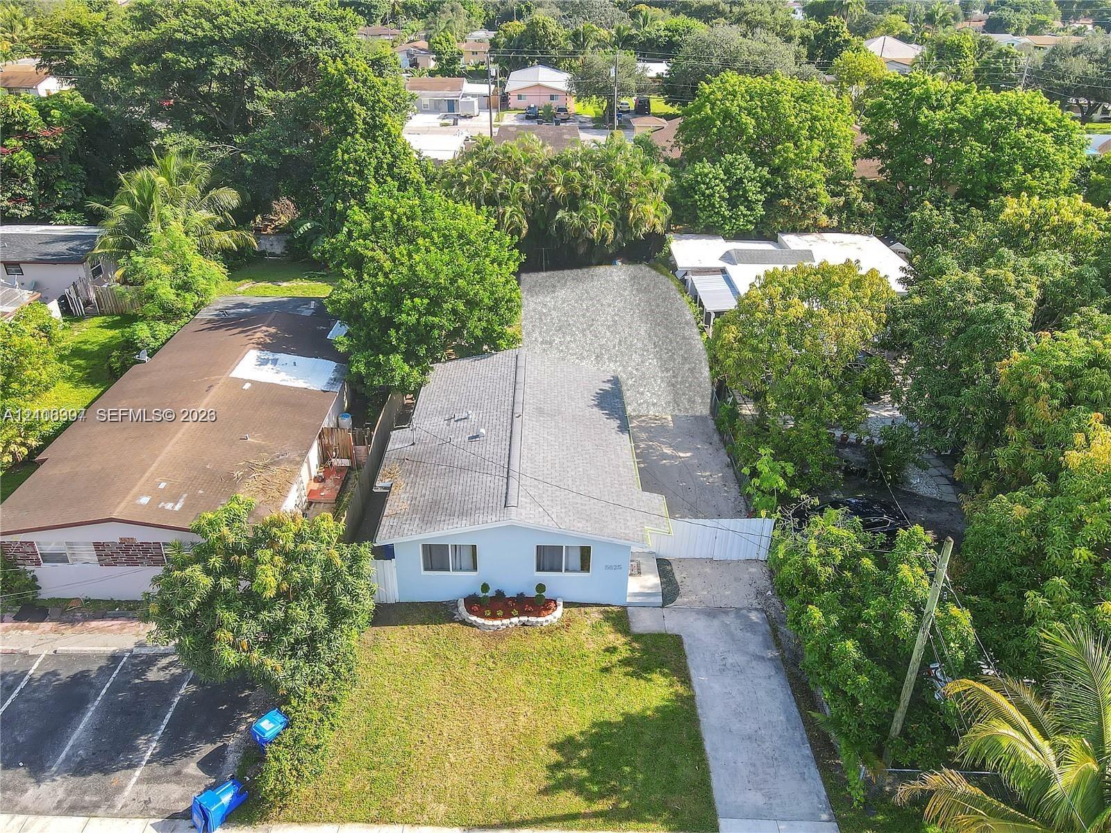 Single-story residence featuring a light-toned exterior, gabled roof, stone-bordered front garden bed, and a paved driveway Single-story residence featuring a light-toned exterior, gabled roof, stone-bordered front garden bed, and a paved driveway