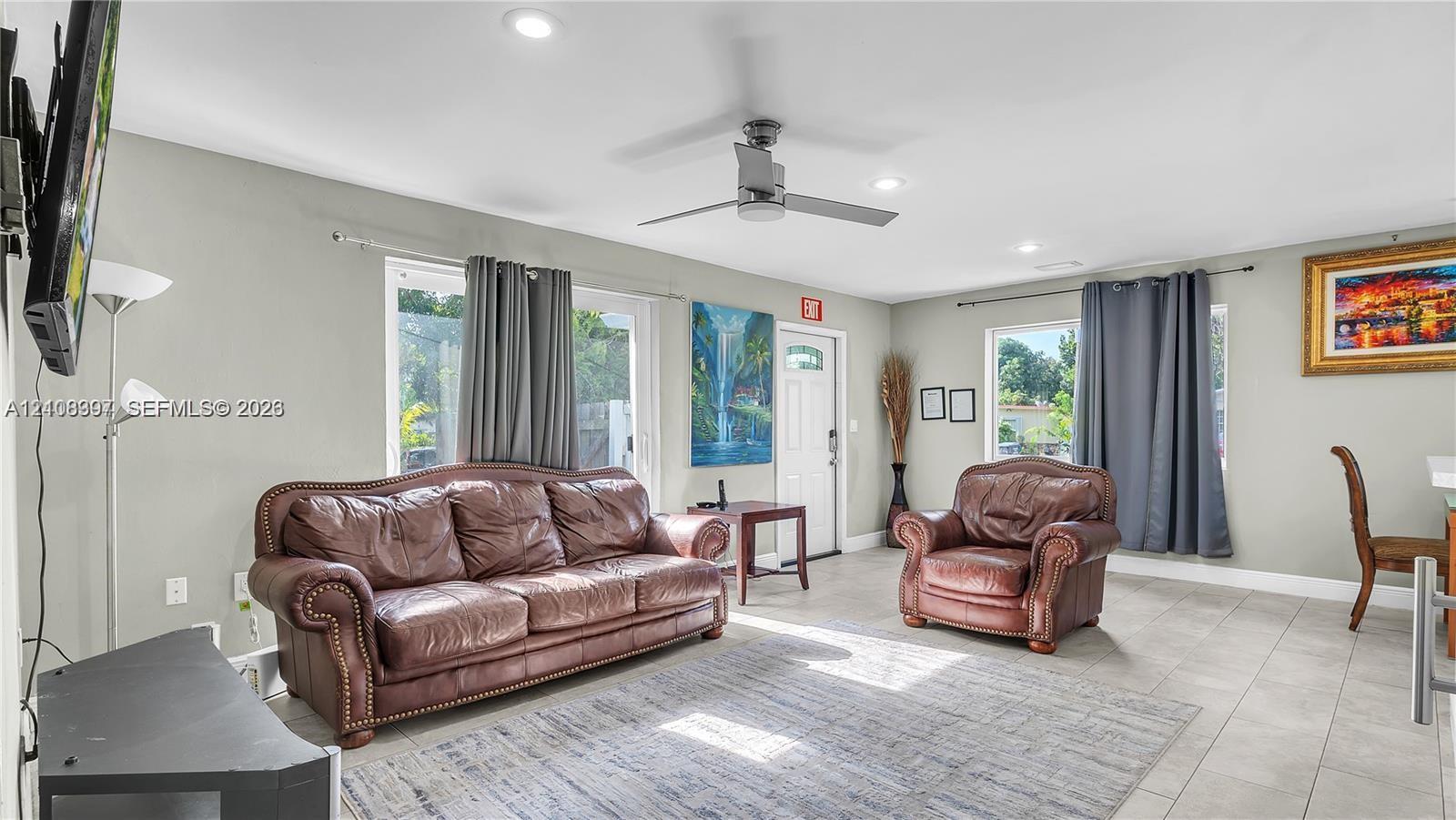 Neutral-toned interior featuring large-format tile flooring, recessed lighting, a ceiling fan, and sliding glass doors