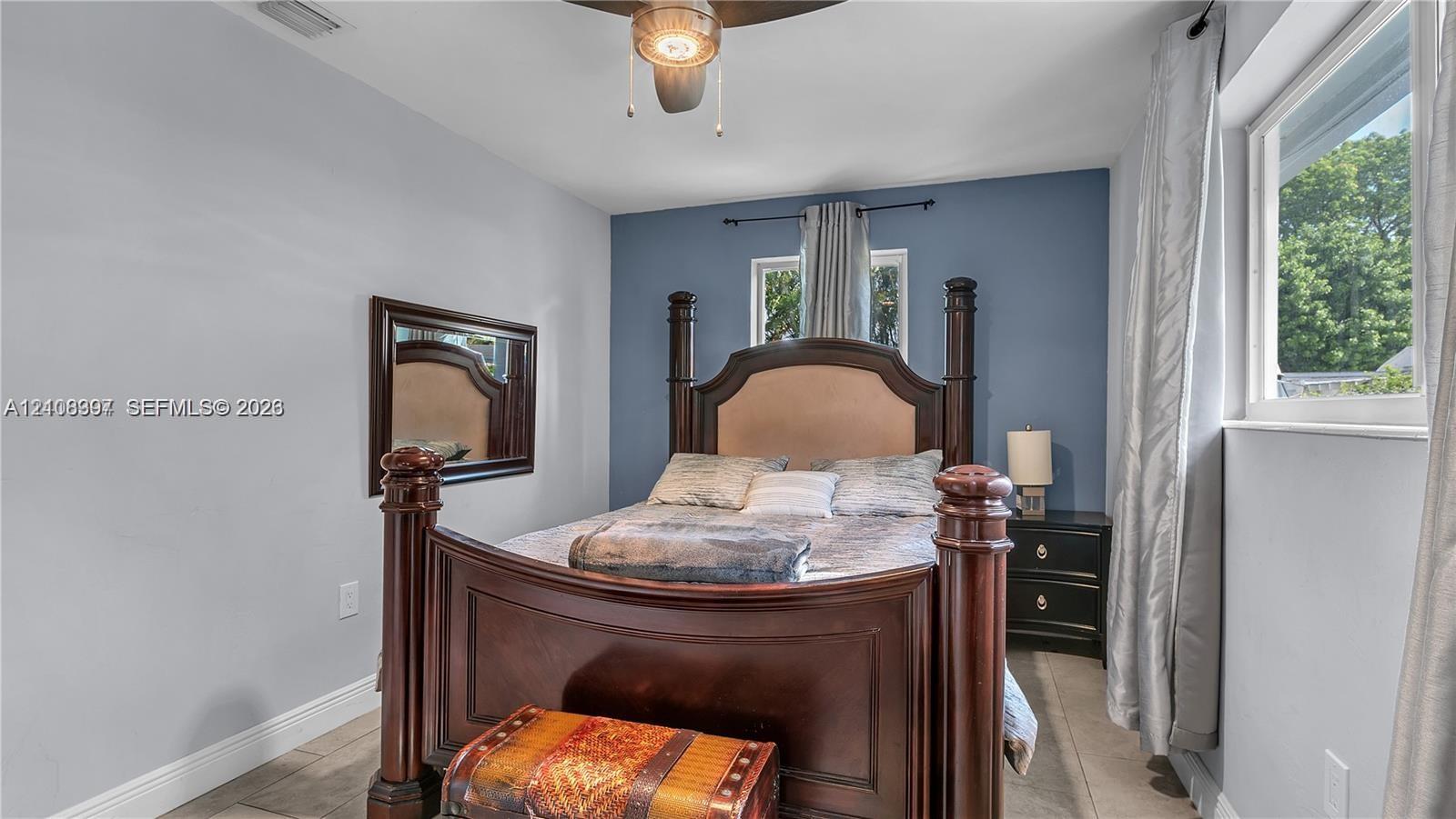 Room featuring neutral wall paint, a blue accent wall, a central ceiling fan with integrated lighting, and dual windows