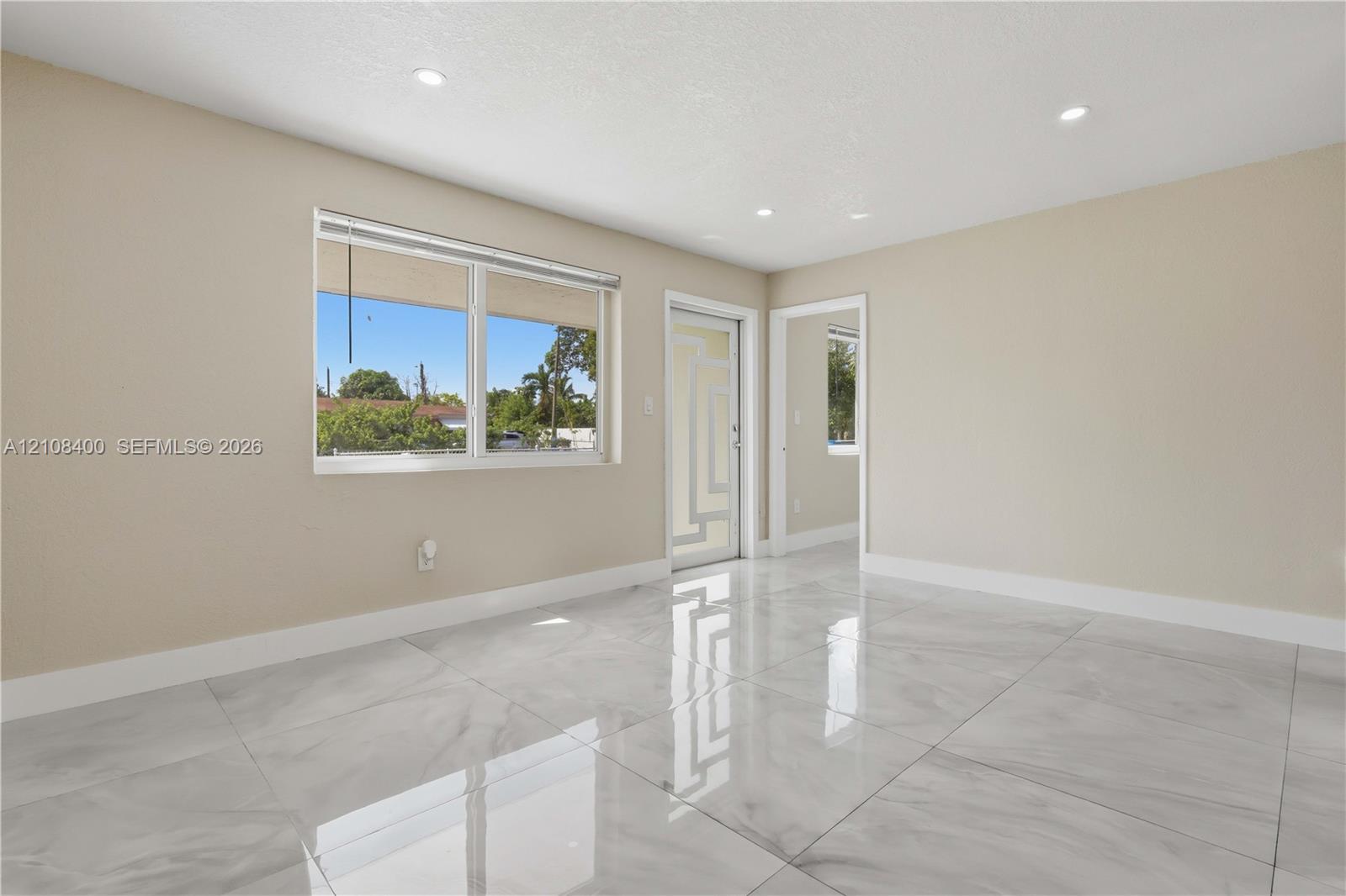 Large-format polished tile flooring, recessed ceiling lighting, and geometric-patterned glass entry door