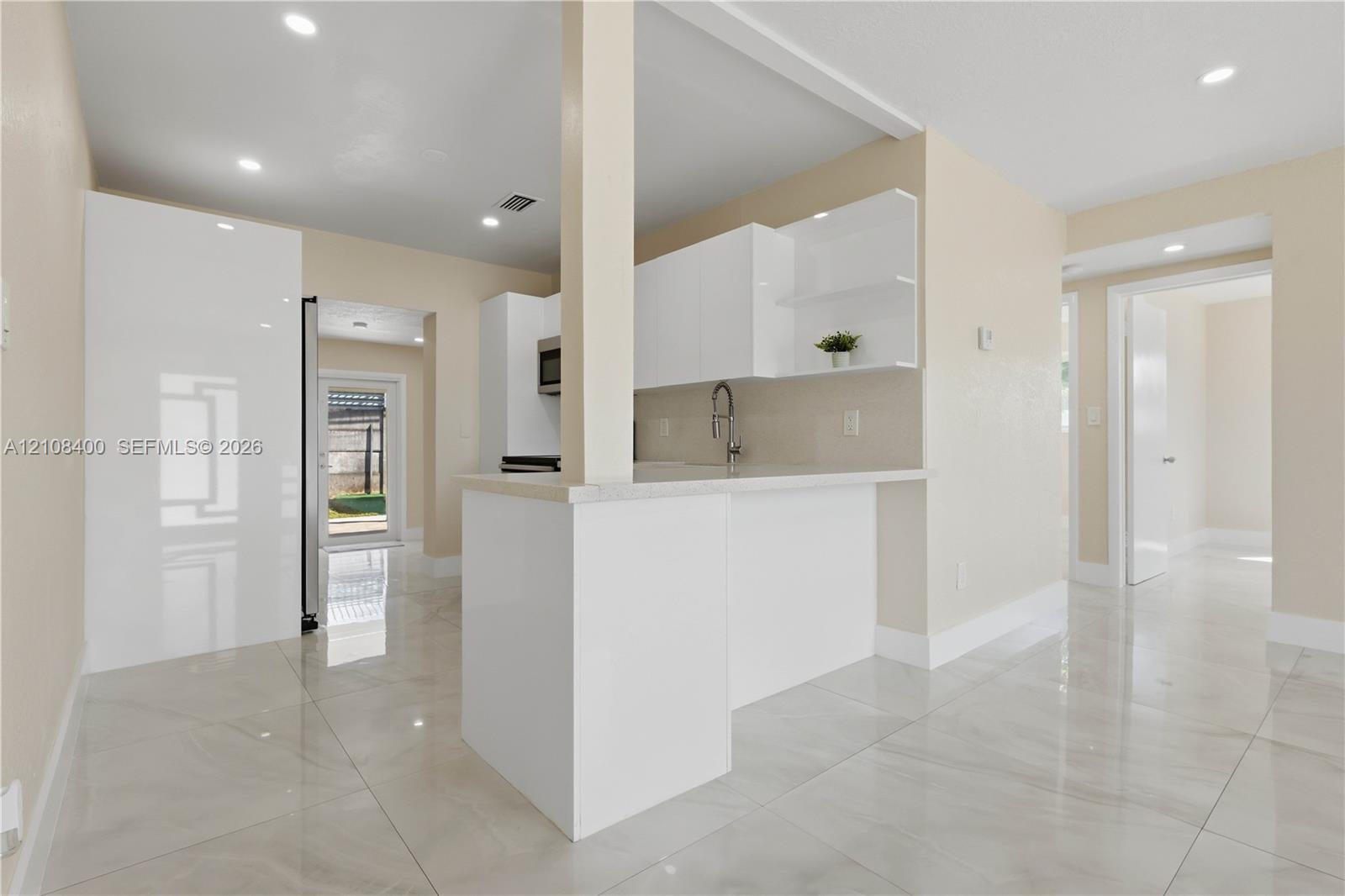 Kitchen featuring high-gloss white cabinetry, white stone countertops, polished tile flooring, and recessed ceiling lighting