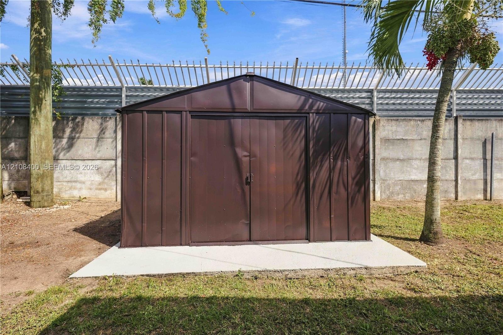 Metal storage structure featuring double doors situated on a concrete slab foundation