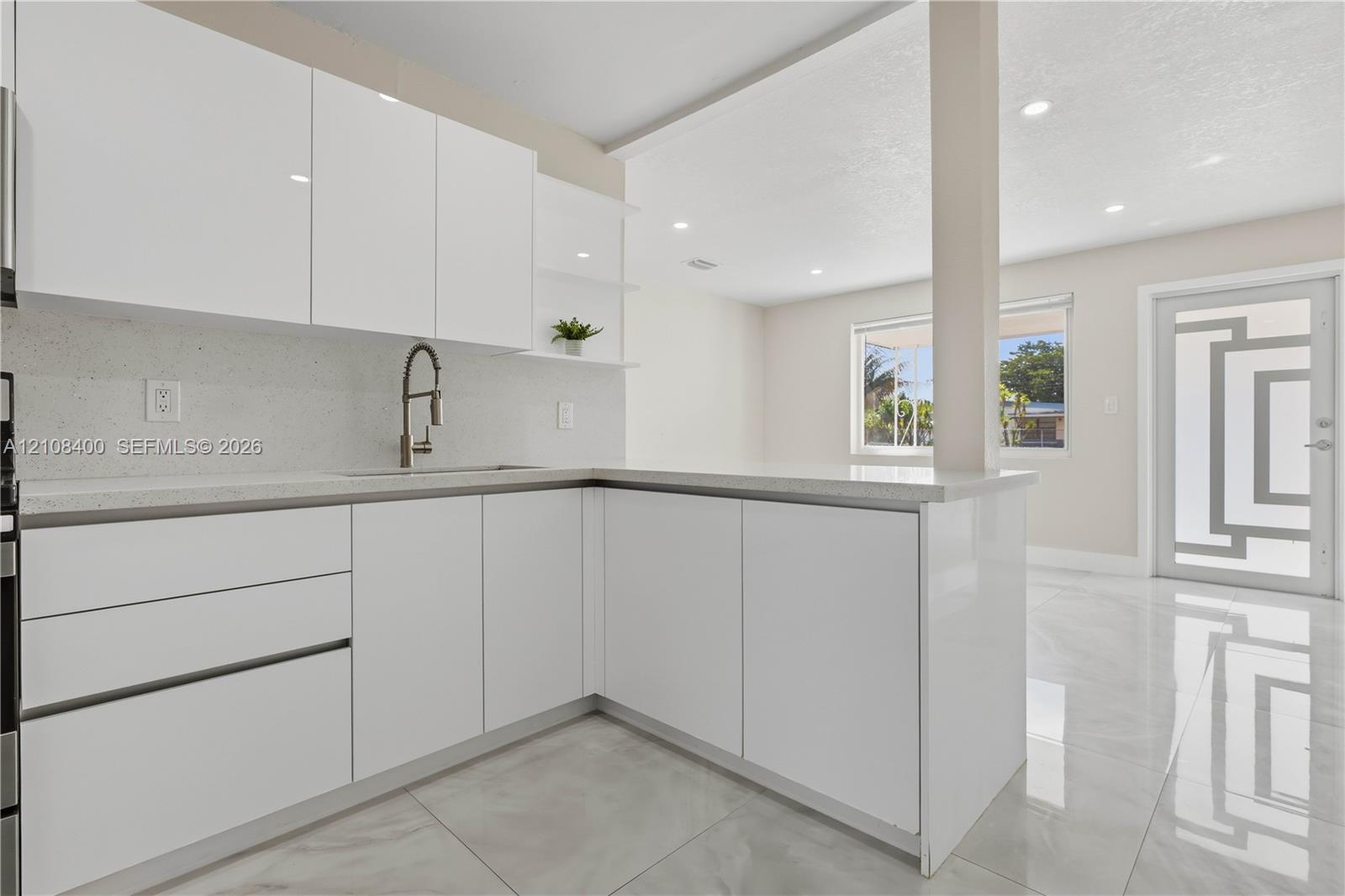 Kitchen featuring high-gloss white cabinetry, quartz countertops, a gooseneck faucet, large-format tile flooring, and a glass-paneled exterior door