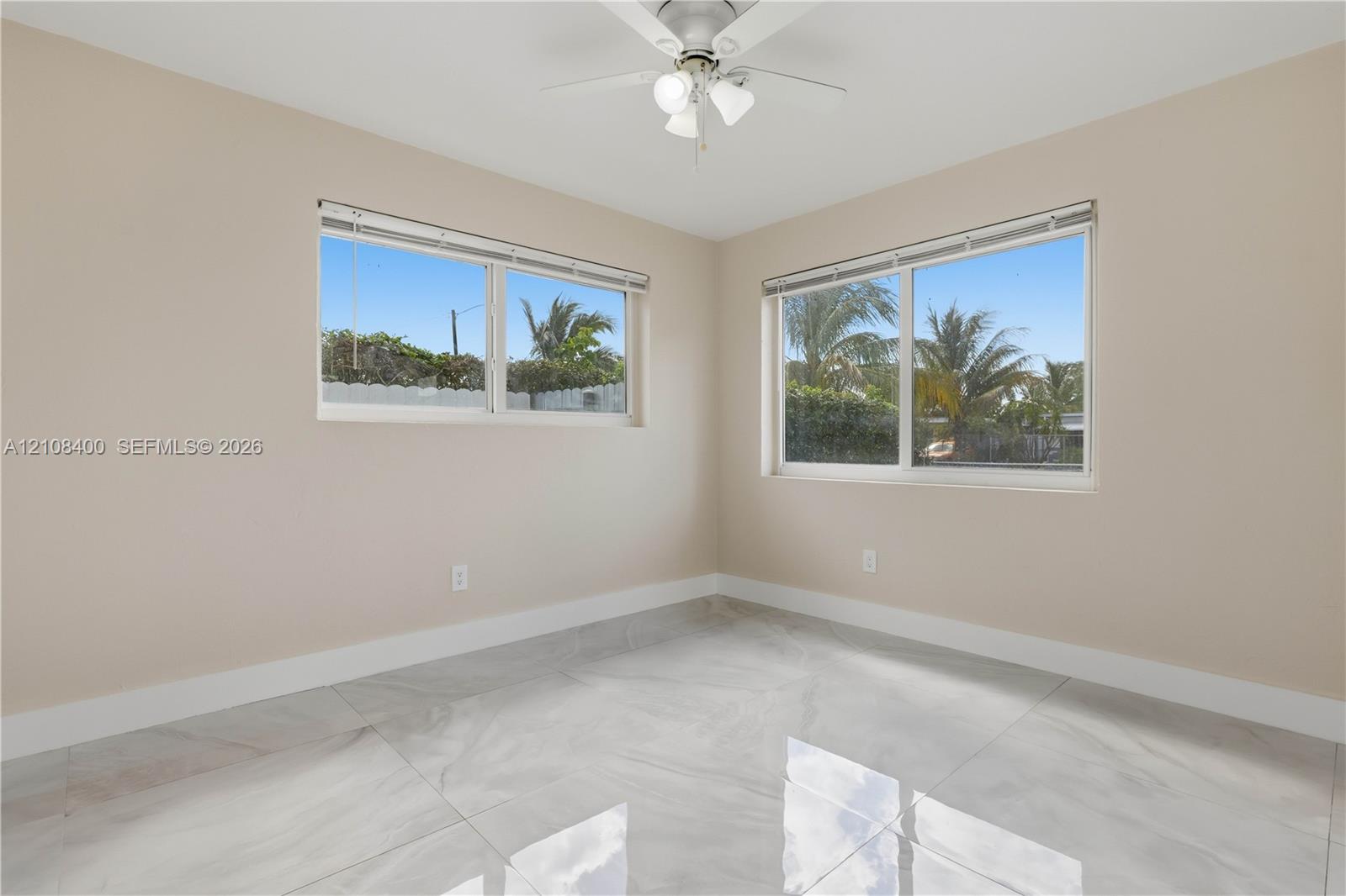 Room featuring large-format tile flooring, dual windows with integrated blinds, and a ceiling-mounted light fixture with a three-blade fan