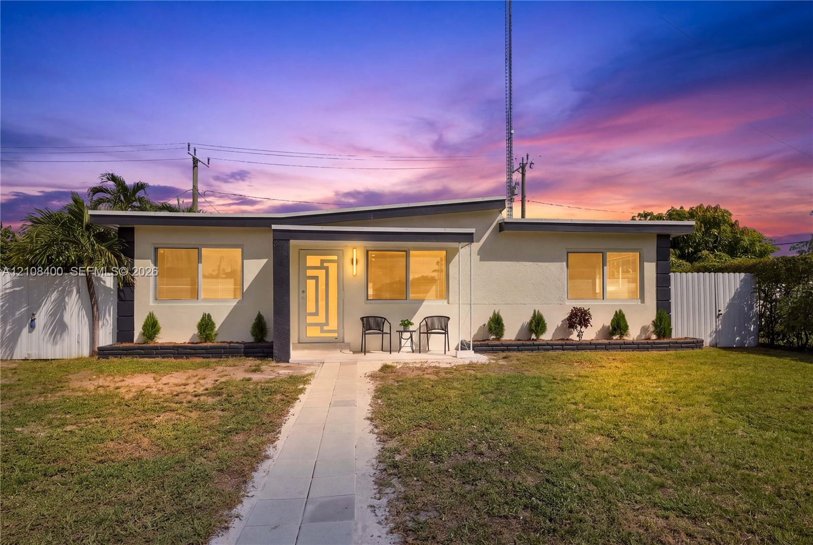Single-story exterior featuring a low-slope roof, stucco siding, geometric glass-panel front door, and a concrete walkway Single-story exterior featuring a low-slope roof, stucco siding, geometric glass-panel front door, and a concrete walkway