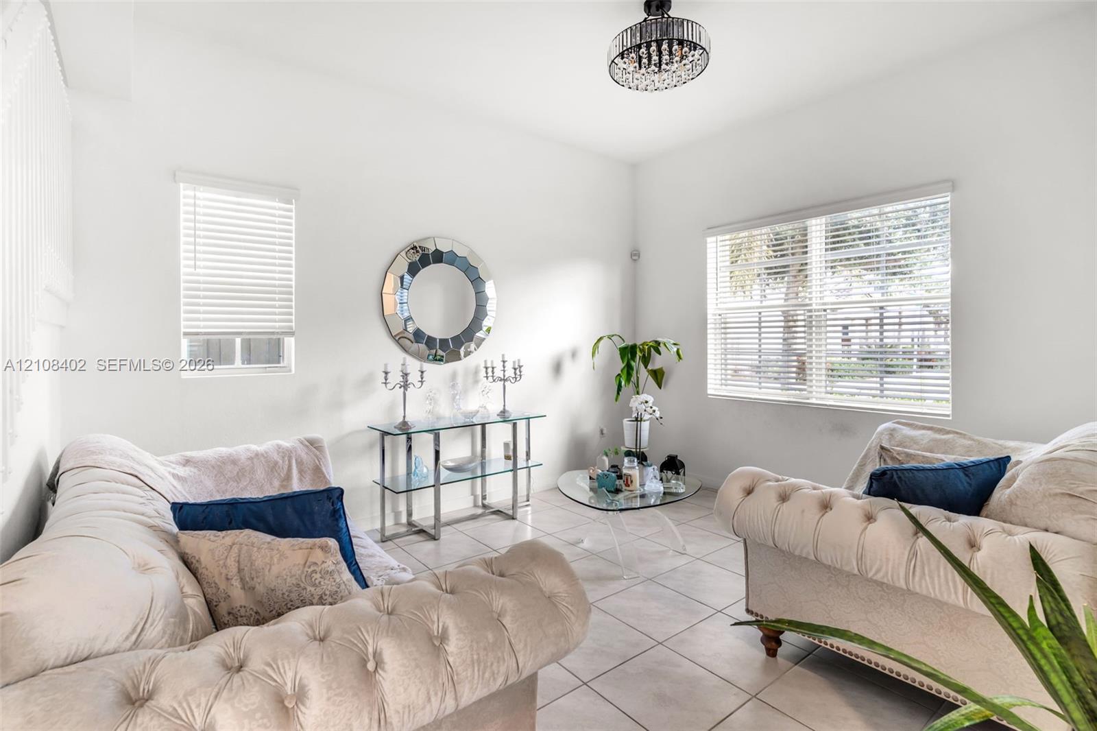 Neutral-toned tile flooring, multi-pane windows with integrated blinds, and a crystal-accented flush-mount chandelier