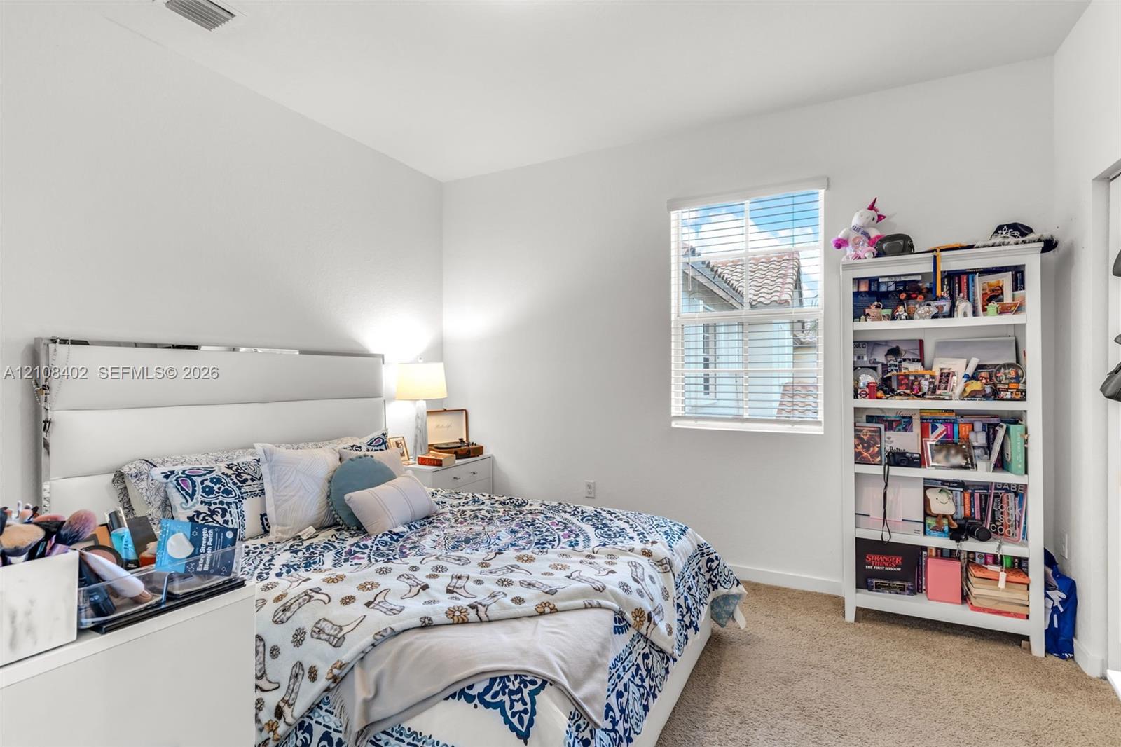 Neutral interior space featuring high ceilings, wall-to-wall carpeting, and a single-hung window with horizontal blinds