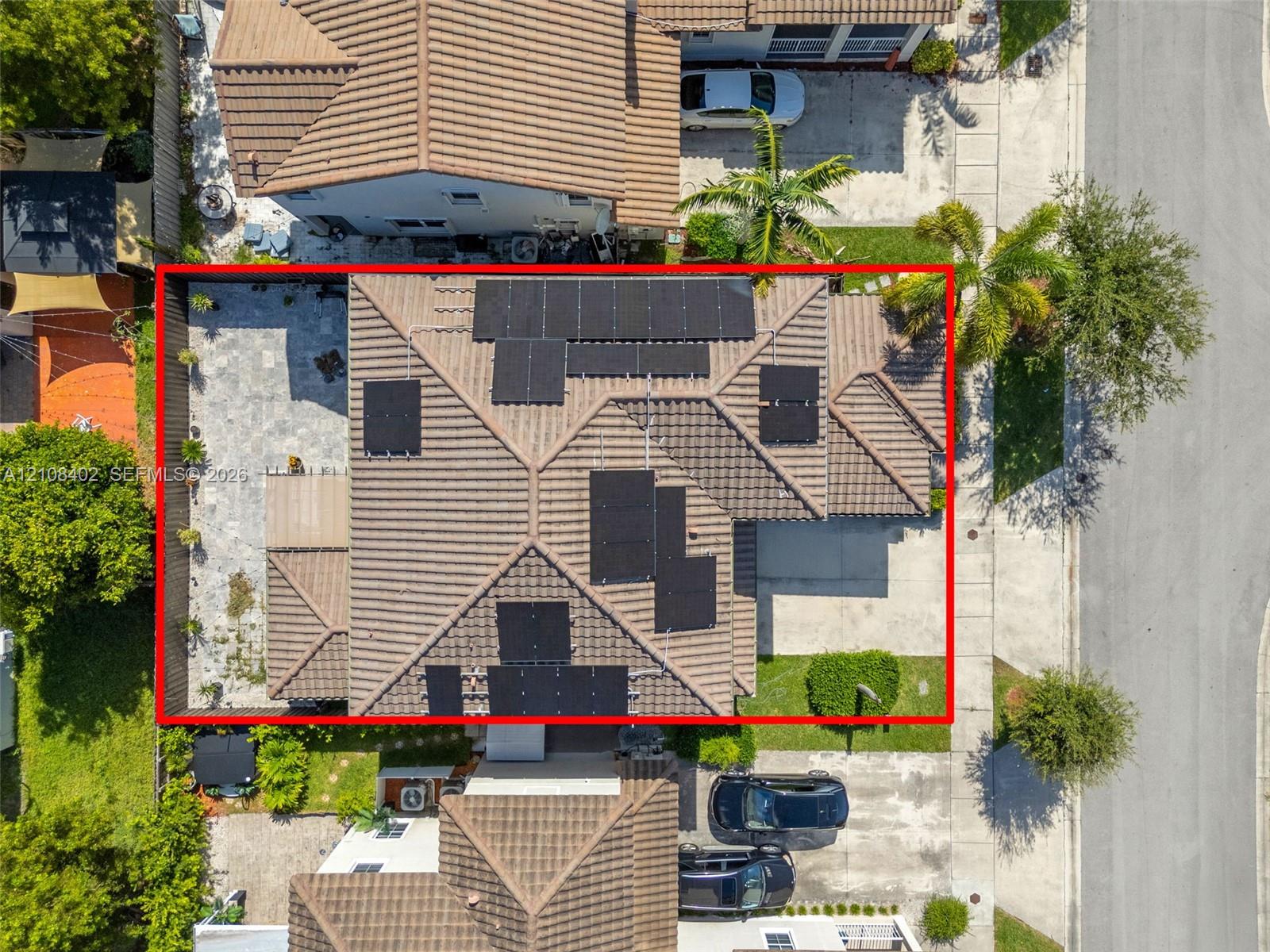 Tile roof featuring integrated solar panels and a paved side patio