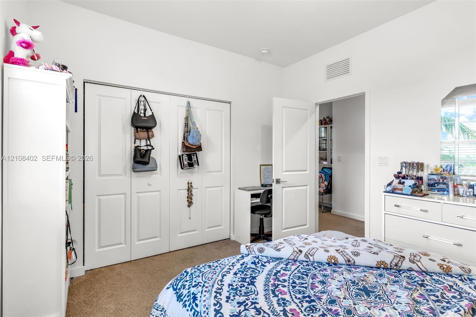 Room featuring neutral wall-to-wall carpeting, white walls, paneled closet doors, and a window with horizontal blinds