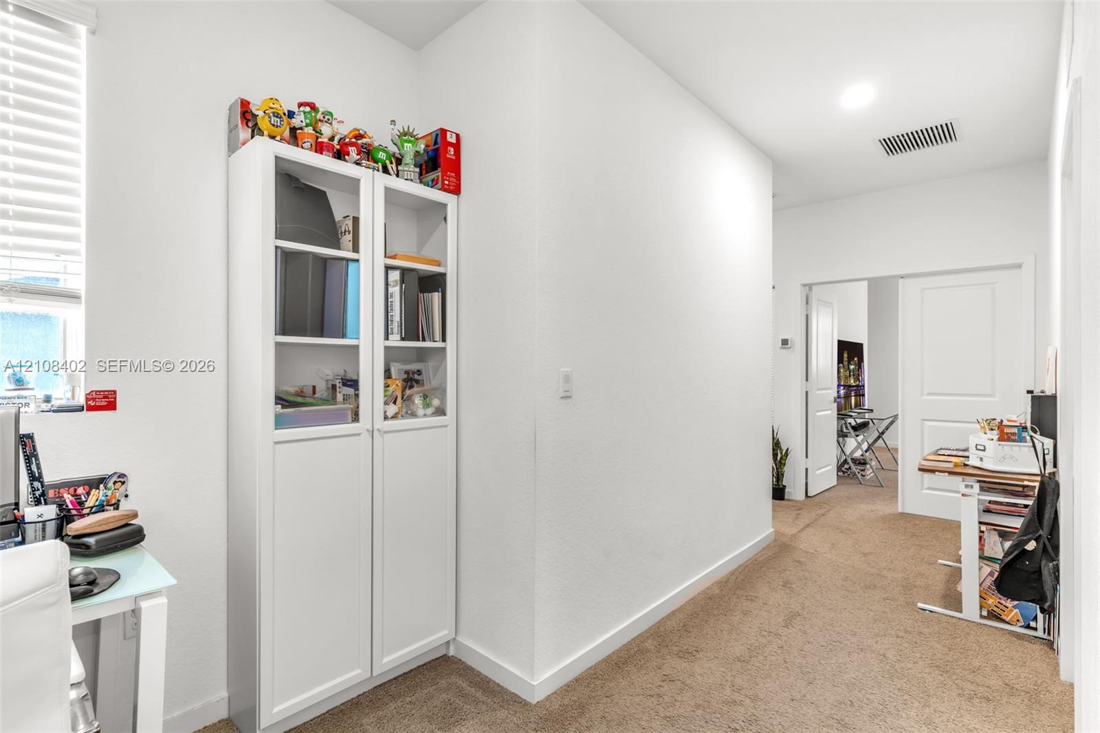 White built-in cabinetry with glass-paneled upper doors, wall-to-wall carpeting, and recessed ceiling lighting