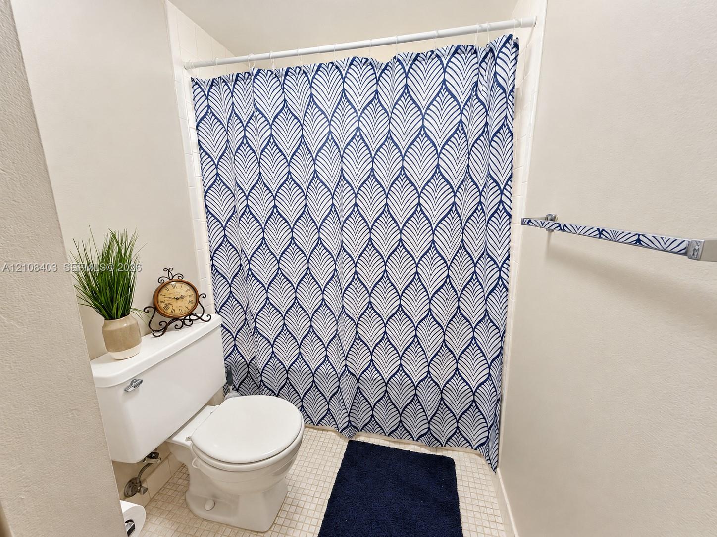 Master Full bathroom featuring white ceramic tile flooring, a wall-mounted towel bar, and a built-in shower enclosure