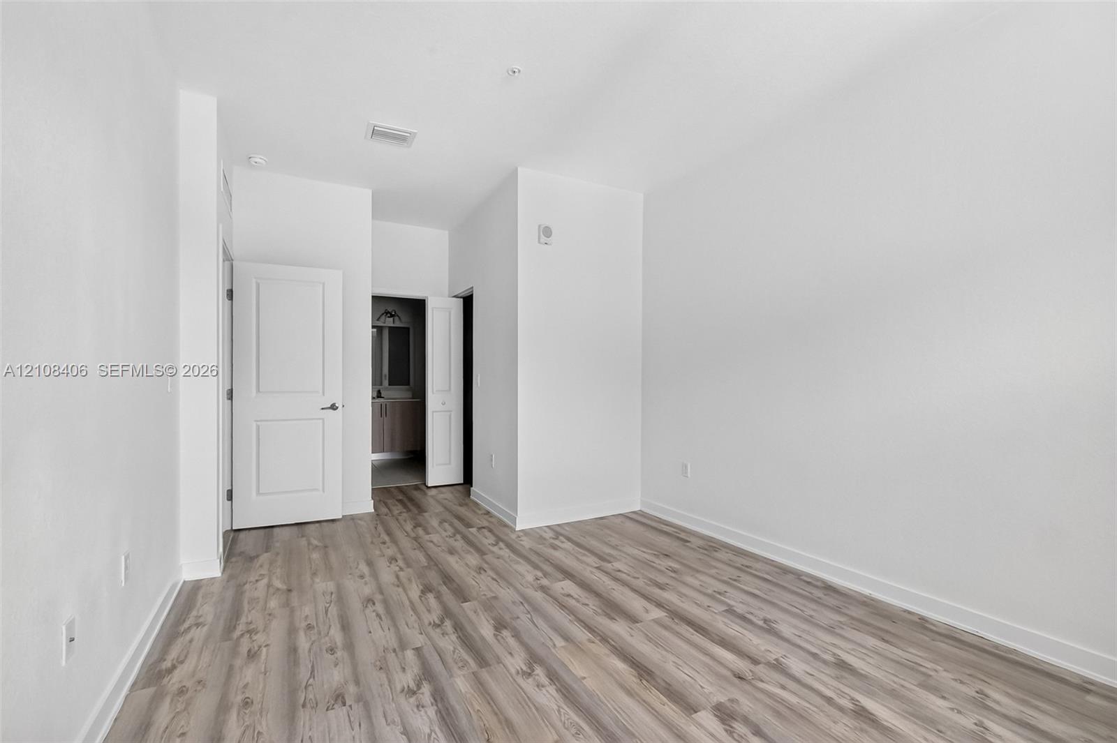 Neutral-toned wood-finish flooring, crisp white walls, and two-panel interior doors