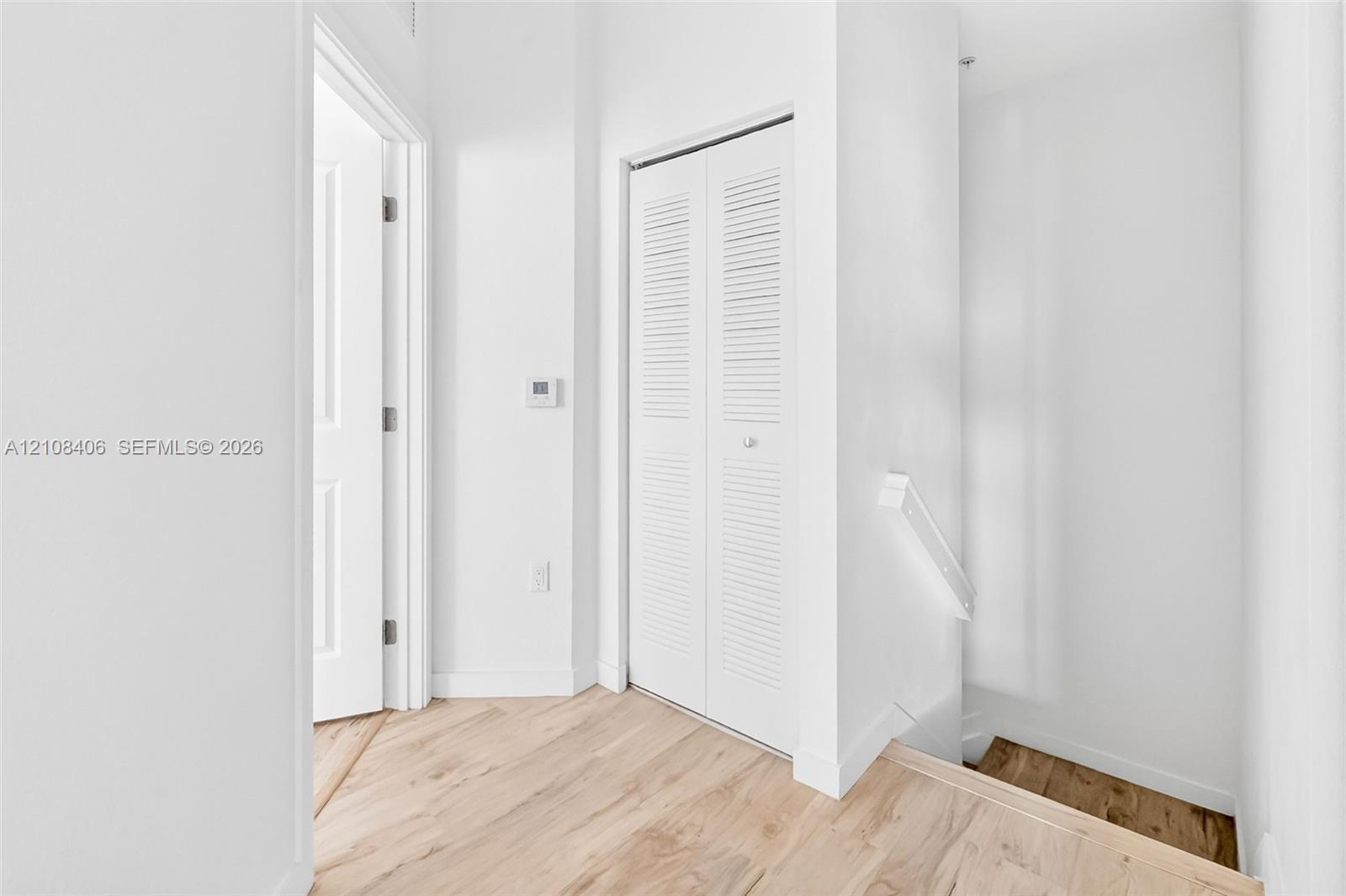 Neutral interior featuring wood-finish flooring, white paneled doors, and a louvered-style closet door