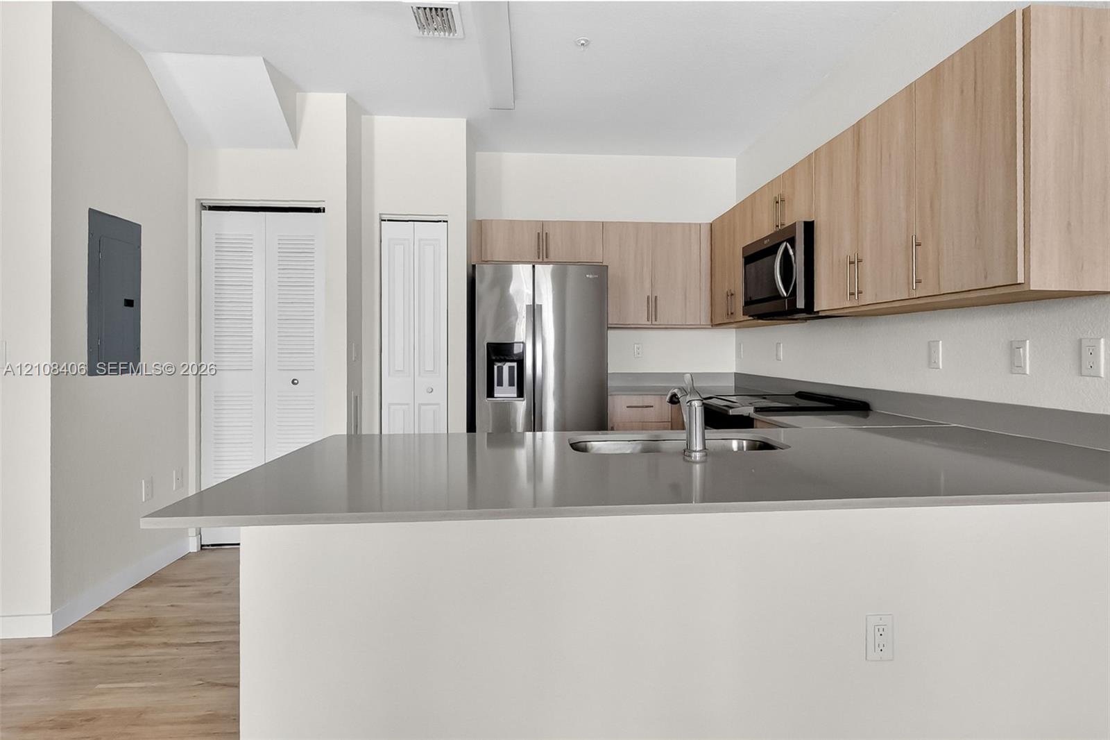 Kitchen featuring light-finish cabinetry, stone-surface countertops, stainless steel appliances, and wood-finish flooring