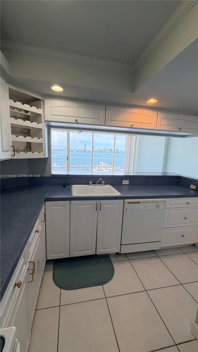 Kitchen featuring white cabinetry with integrated wine storage, contrasting countertops, a drop-in sink, and tile flooring