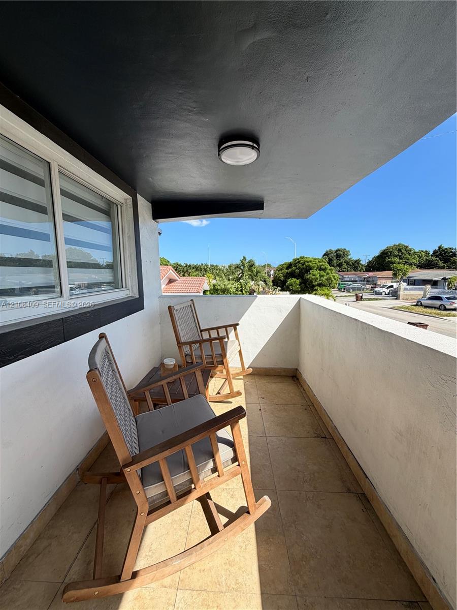 Covered balcony featuring tile flooring, smooth stucco walls, and a flush-mount ceiling light fixture