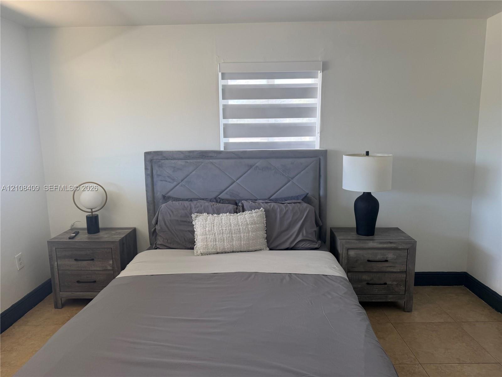 Neutral-toned interior room featuring tile flooring and a dual-shade roller window covering