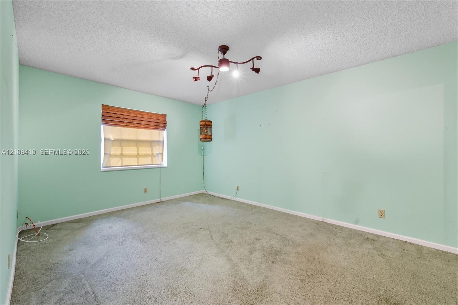 Interior room featuring wall-to-wall carpeting, textured ceiling, and a multi-arm spotlight fixture with a hanging accent pendant