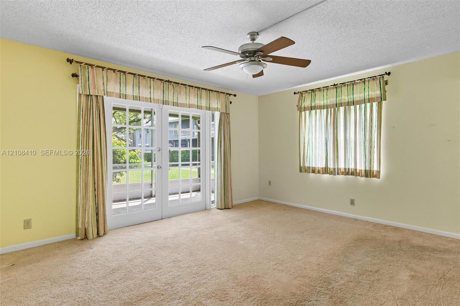 Room featuring carpeted flooring, a ceiling fan with integrated lighting, and white-framed glass paneled exterior doors