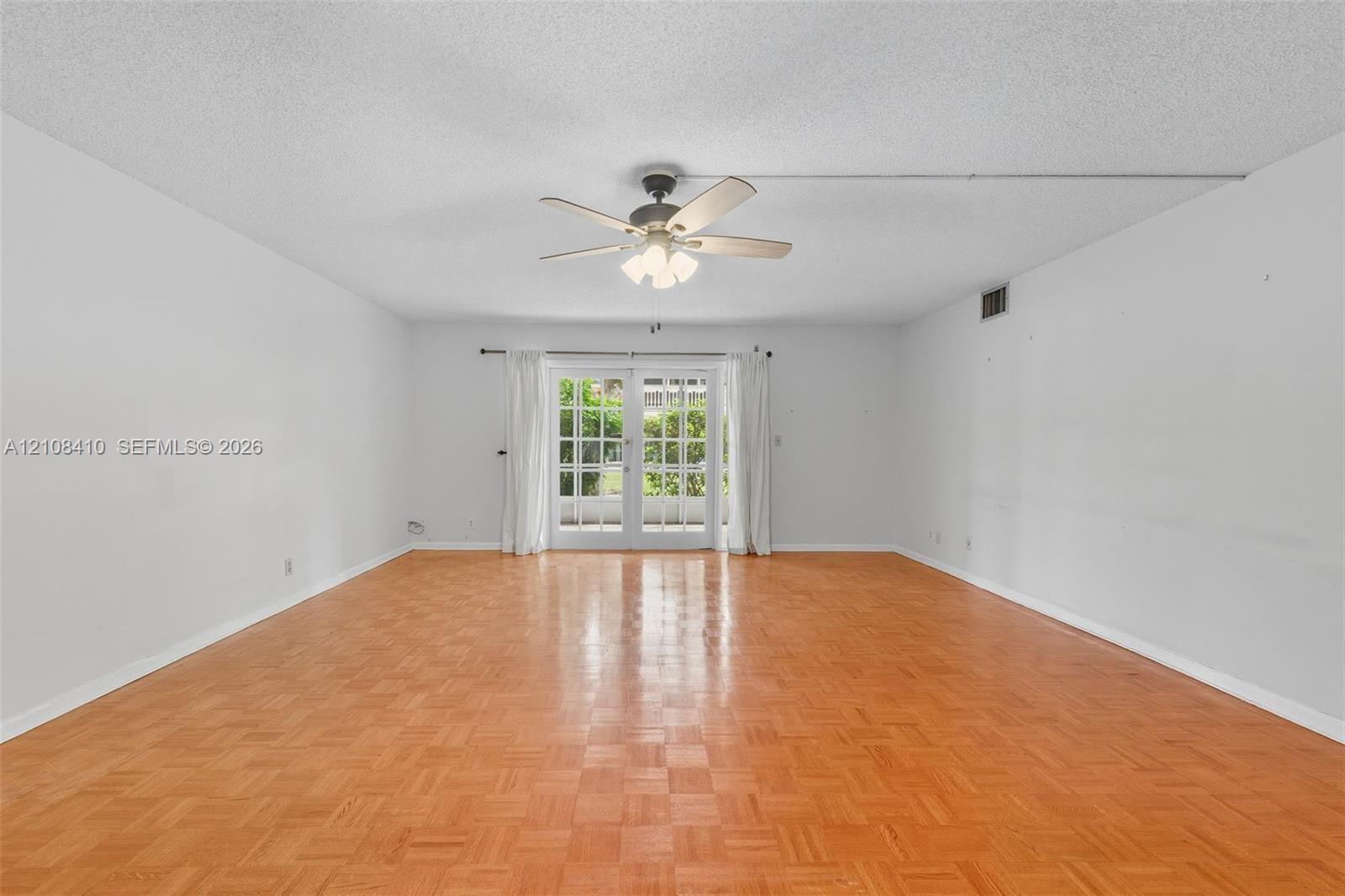 Parquet wood-finish flooring, ceiling fan with integrated lighting, and glass-paned French doors Parquet wood-finish flooring, ceiling fan with integrated lighting, and glass-paned French doors