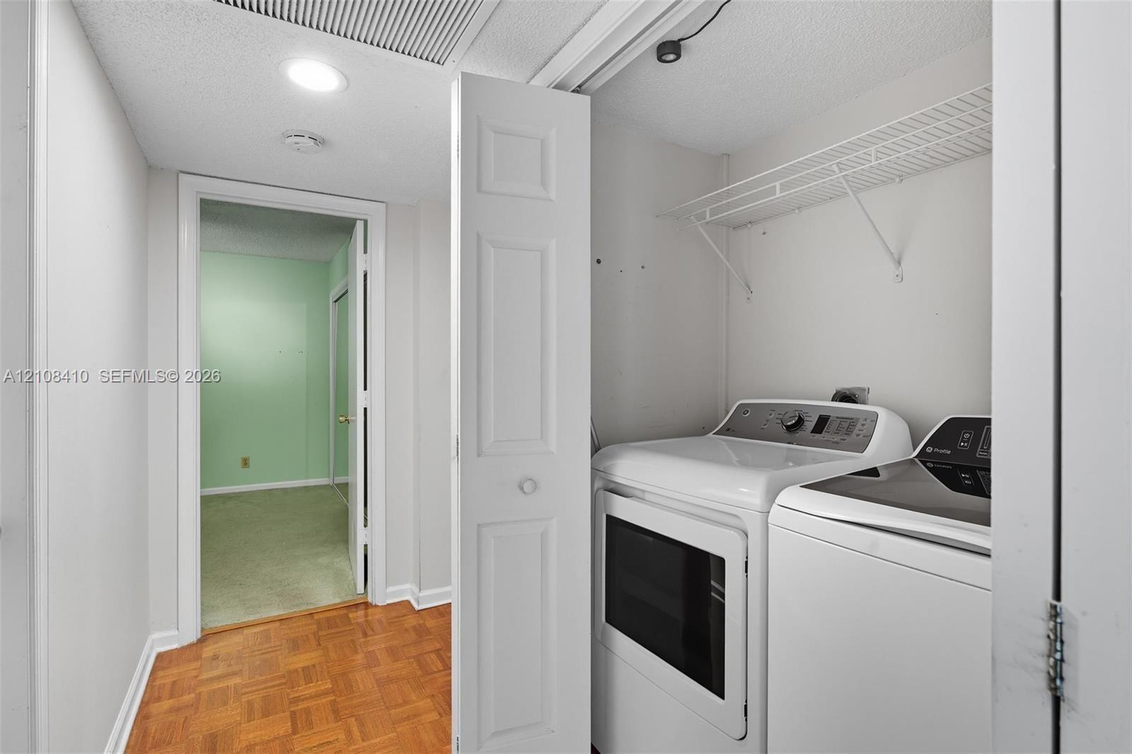 Laundry closet featuring white bifold doors, wire shelving, and wood-finish parquet flooring Laundry closet featuring white bifold doors, wire shelving, and wood-finish parquet flooring