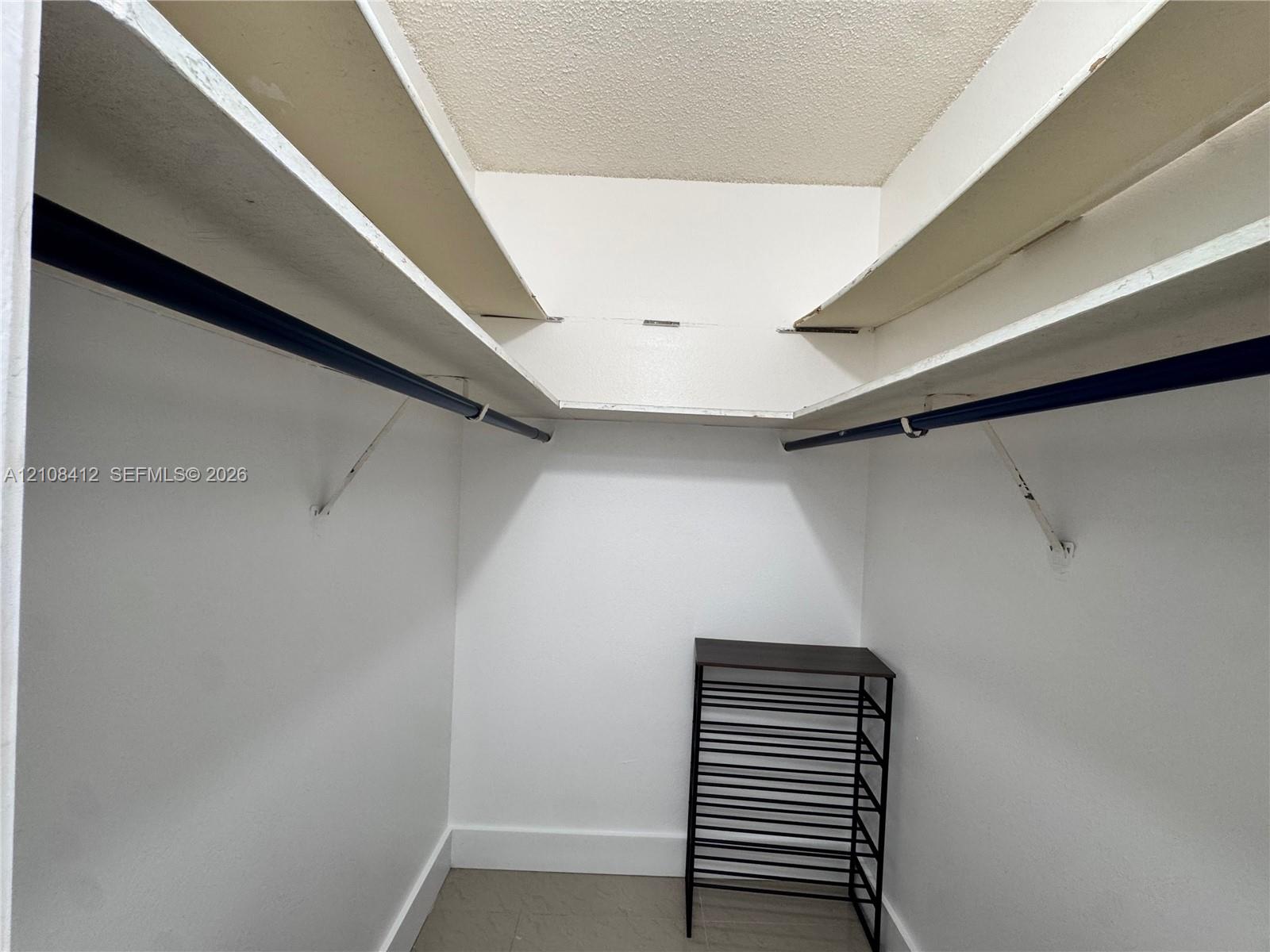 Storage space featuring white built-in shelving and dual hanging rods