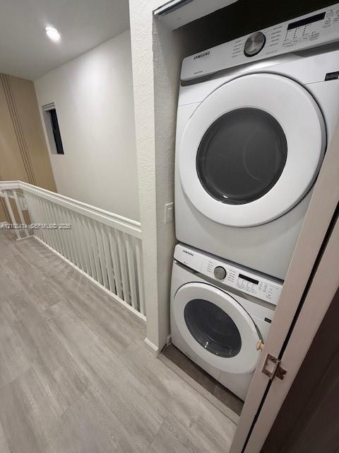 Stackable washer and dryer unit with white finish, wood-finish flooring, and white spindle railing