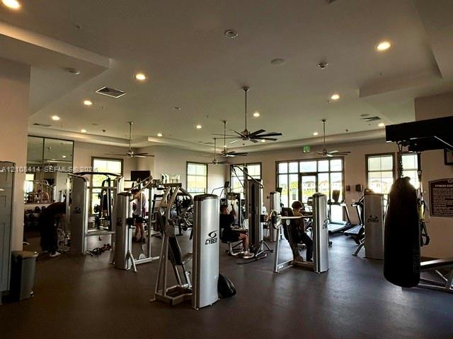 Fitness facility featuring recessed lighting, ceiling fans, multiple large windows, and wall-mounted mirrors