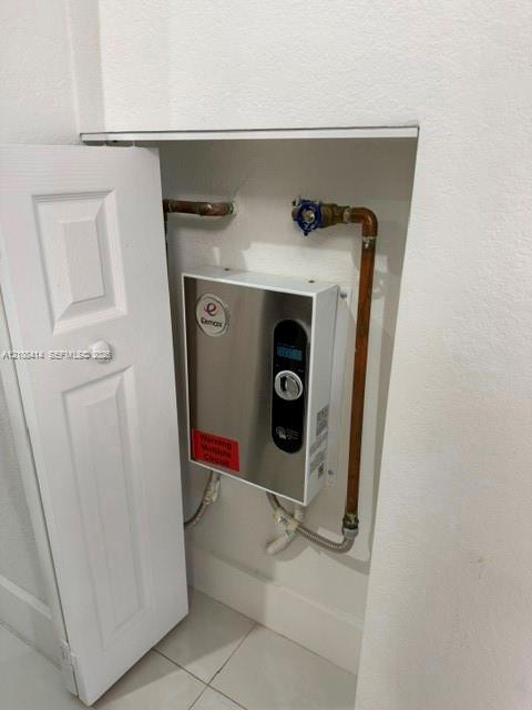 Wall-mounted tankless electric water heater featuring a digital control panel and stainless steel finish, enclosed within a recessed utility cabinet