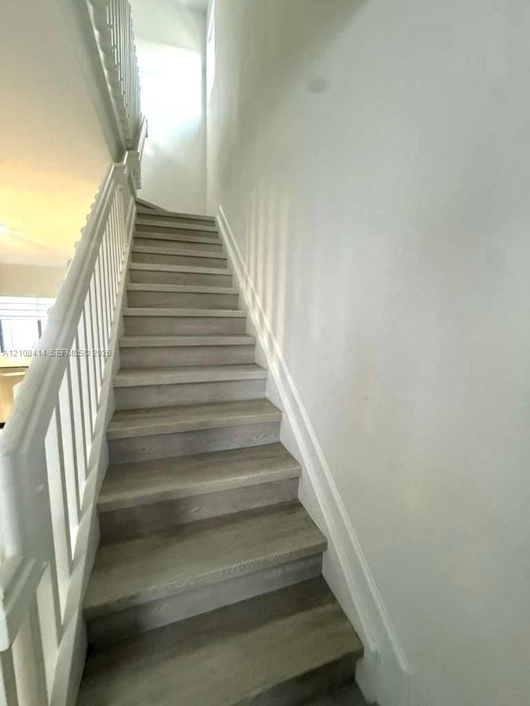 Staircase featuring wood-finish treads and a white painted balustrade with a matching handrail