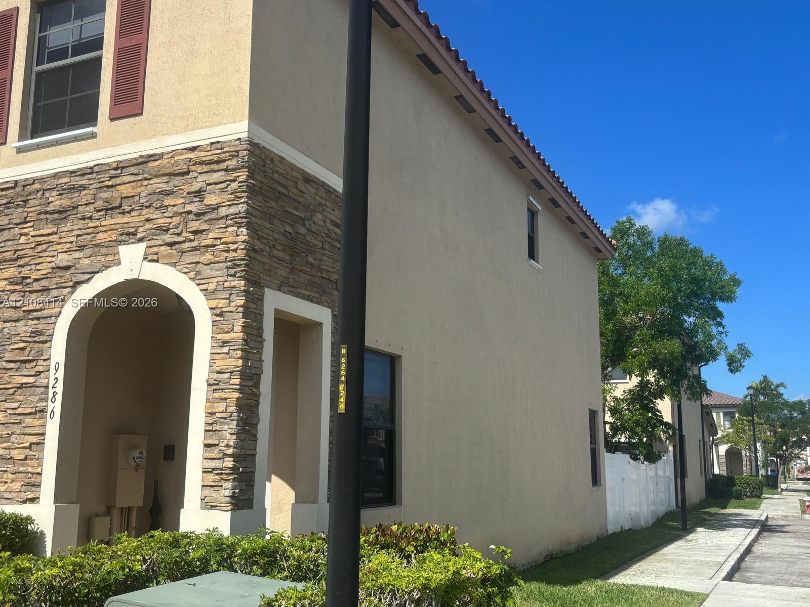 Exterior featuring stucco siding, stone veneer accents, arched entryway, and clay tile roof